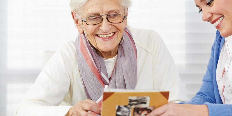 Seniorin lest in einem Buch, unterstützt durch den Pflegedienst Hermine.